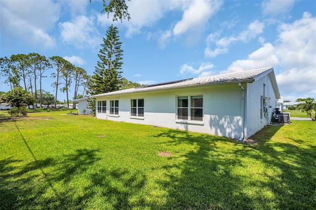 rear view of house featuring stucco siding, a yard, and central AC unit