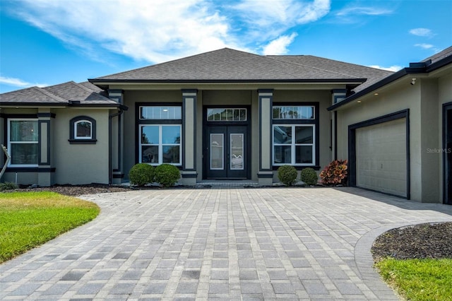 655 Whisper Woods Dr, Lakeland, FL 33813 - view of exterior entry with a shingled roof, a garage, decorative driveway, stucco siding, and french doors