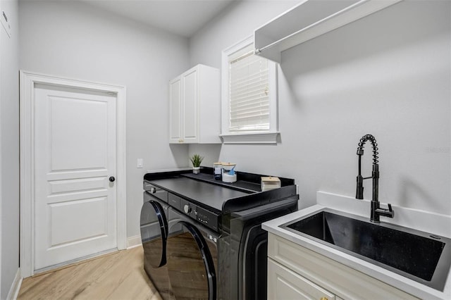 655 Whisper Woods Dr, Lakeland, FL 33813 - laundry room featuring cabinet space, washing machine and clothes dryer, light wood finished floors, a sink, and baseboards