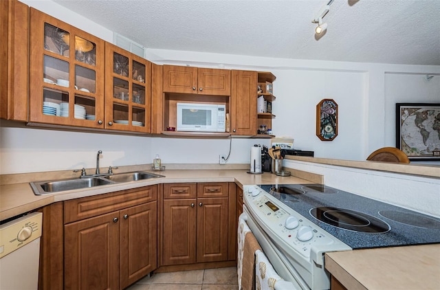 kitchen featuring white appliances, a textured ceiling, a sink, and light countertops