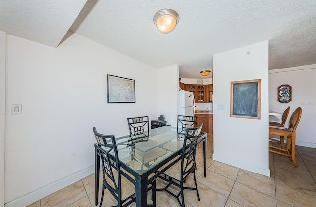 dining area featuring a textured ceiling, baseboards, and light tile patterned floors