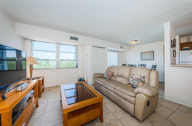 living area with visible vents, a textured ceiling, and light tile patterned floors