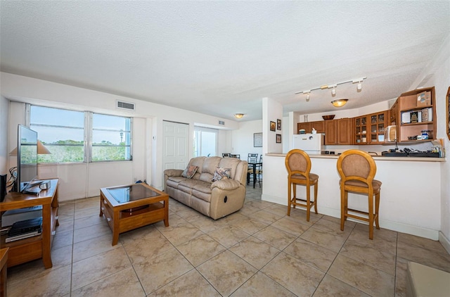 living area featuring visible vents, a textured ceiling, plenty of natural light, and light tile patterned flooring