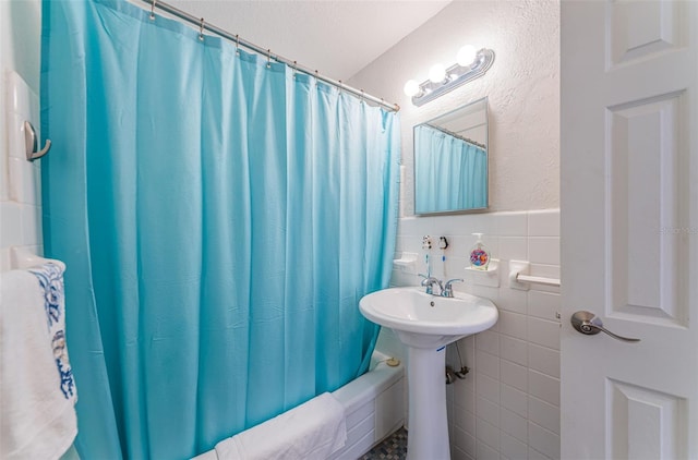 bathroom featuring tile walls, wainscoting, and shower / tub combo