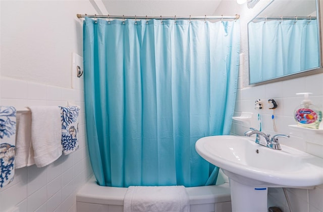 bathroom featuring tasteful backsplash, shower / bath combination with curtain, and tile walls