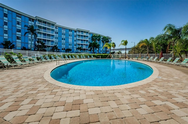 community pool with a patio and fence