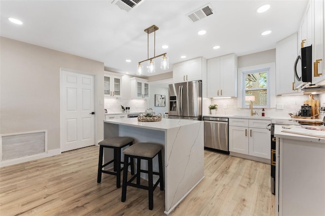 7494 7th St N, Saint Petersburg, FL 33702 - kitchen featuring visible vents, light wood finished floors, a kitchen island, and stainless steel appliances