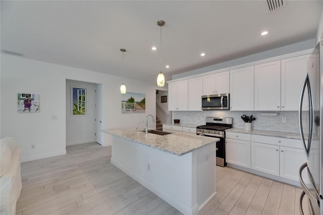 5814 Silver Sun Dr, Apollo Beach, FL 33572 - kitchen featuring appliances with stainless steel finishes, a sink, backsplash, light wood finished floors, and a kitchen island with sink