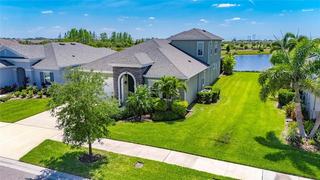5814 Silver Sun Dr, Apollo Beach, FL 33572 - view of front of house with stucco siding, a shingled roof, a front yard, concrete driveway, and a water view
