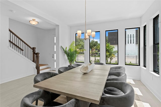 dining space featuring stairway, a chandelier, a wealth of natural light, and baseboards