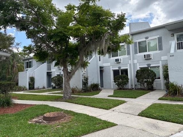 4127 Dolphin Dr Unit 4127, Tampa, FL 33617 - view of property featuring an AC wall unit, stucco siding, and a front yard