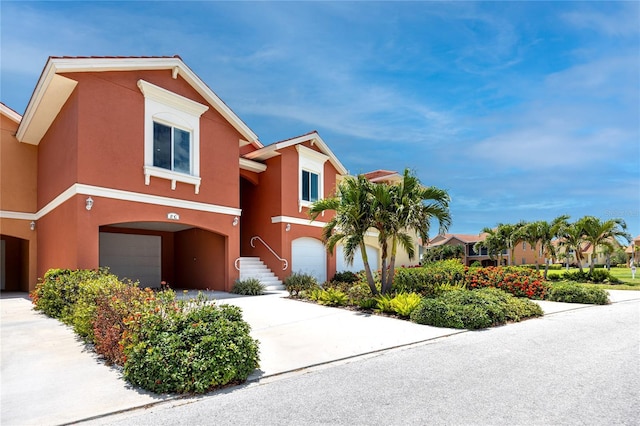 view of property with an attached garage, stucco siding, and concrete driveway