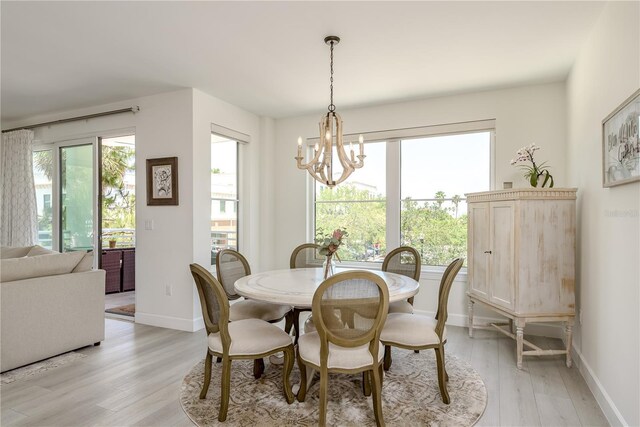 dining area with an inviting chandelier, baseboards, and light wood-type flooring