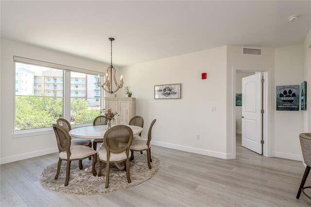 dining room with baseboards, light wood-type flooring, a chandelier, and visible vents
