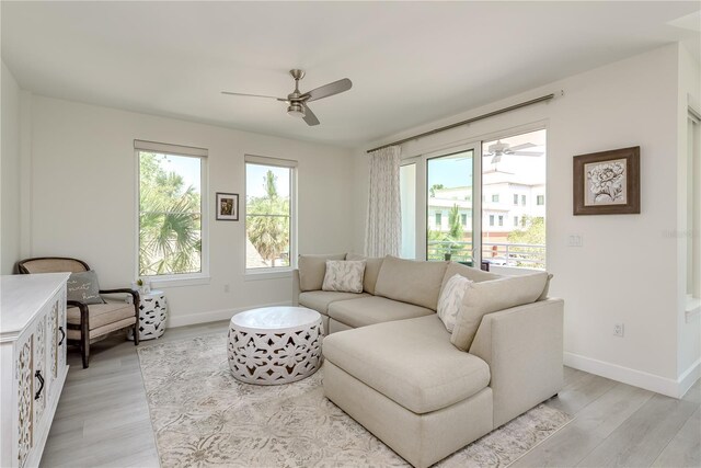 living room with light wood-type flooring, a ceiling fan, and baseboards