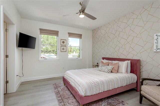 bedroom featuring baseboards, an accent wall, light wood-style flooring, and tile walls