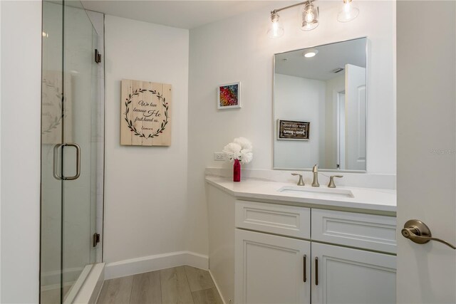 bathroom with baseboards, a shower stall, wood finished floors, and vanity