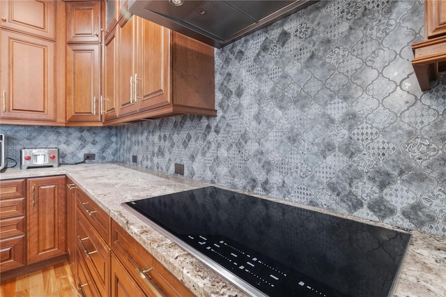 1432 Gopher Loop, Tarpon Springs, FL 34689 - kitchen with light stone counters, light wood-style flooring, black electric stovetop, and brown cabinets