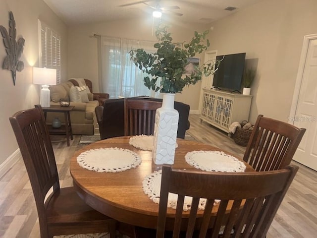 dining room with visible vents, light wood-style floors, baseboards, ceiling fan, and vaulted ceiling