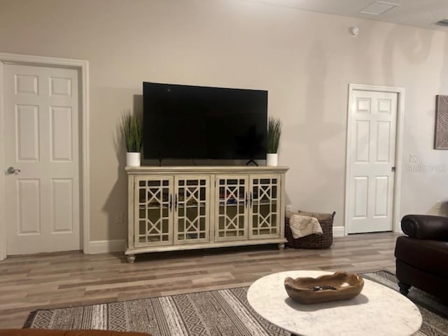 living room with baseboards, visible vents, and wood finished floors