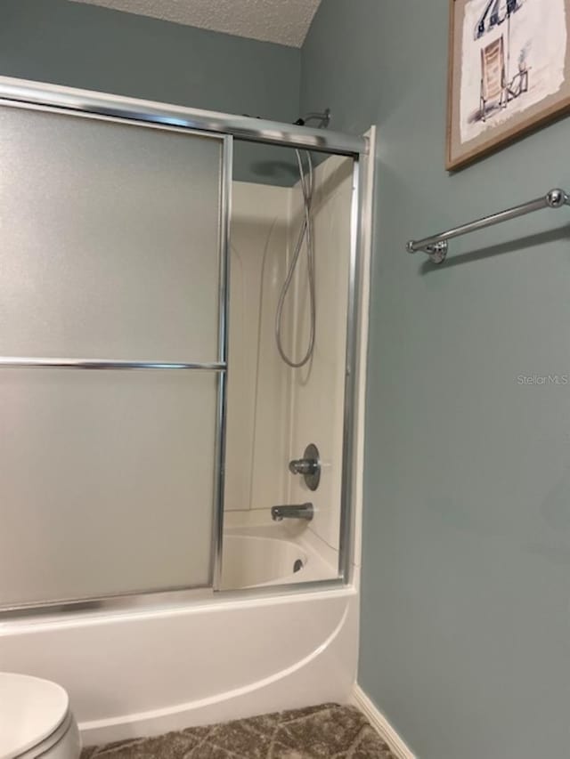 full bath with a textured ceiling, tile patterned floors, baseboards, toilet, and shower / bath combination with glass door