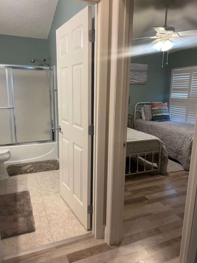 full bath featuring wood finished floors, ensuite bathroom, ceiling fan, a textured ceiling, and enclosed tub / shower combo