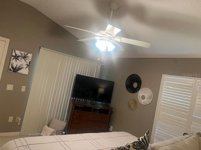 bedroom featuring a ceiling fan, vaulted ceiling, and a textured ceiling