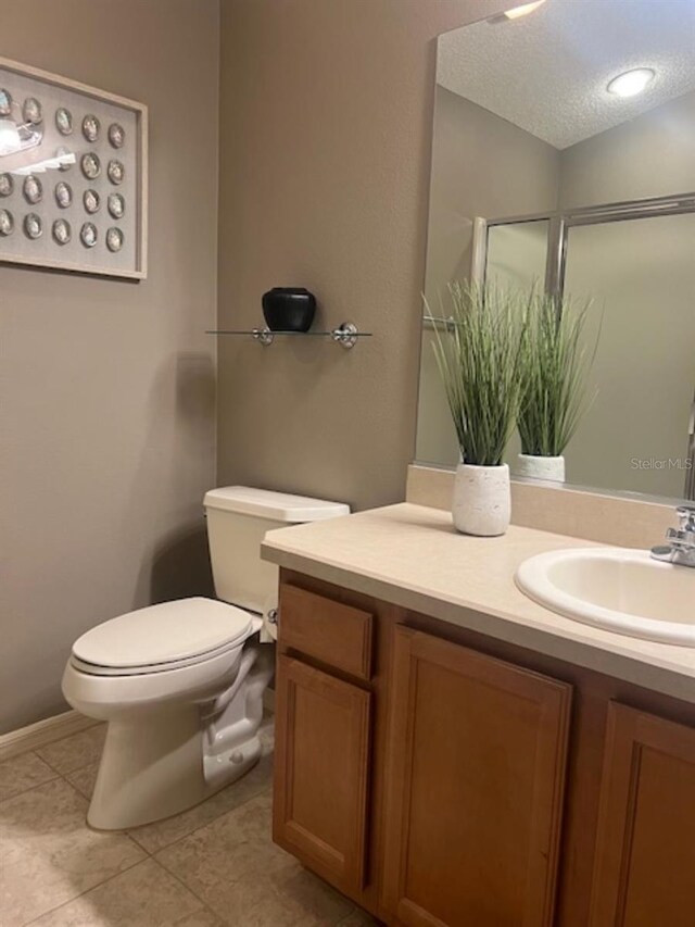 bathroom featuring toilet, a textured ceiling, tile patterned flooring, and vanity