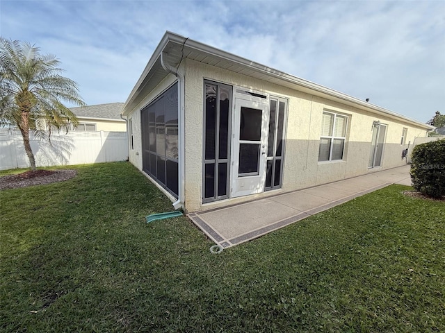 view of side of property featuring fence, stucco siding, and a yard