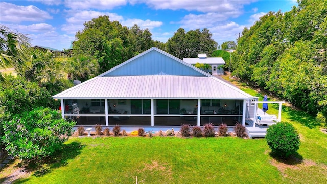 back of property featuring a lawn, metal roof, and a sunroom