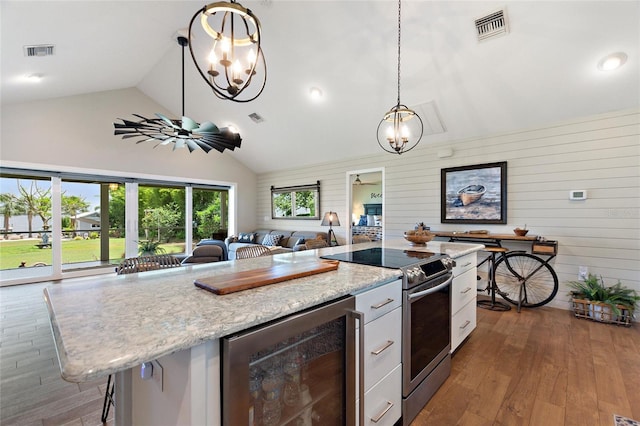 kitchen featuring visible vents, stainless steel range with electric stovetop, beverage cooler, open floor plan, and an inviting chandelier