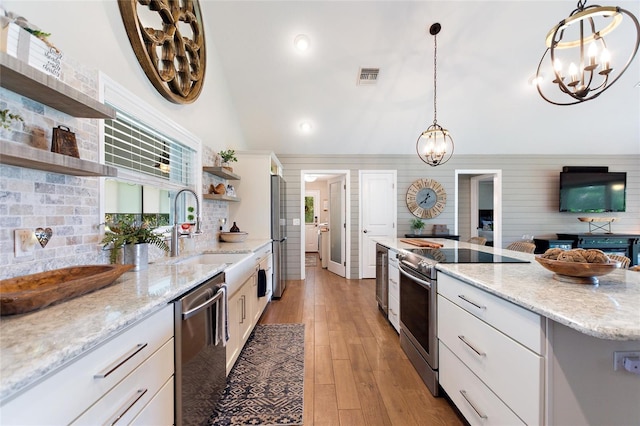 kitchen featuring open shelves, appliances with stainless steel finishes, a sink, light wood-style flooring, and visible vents