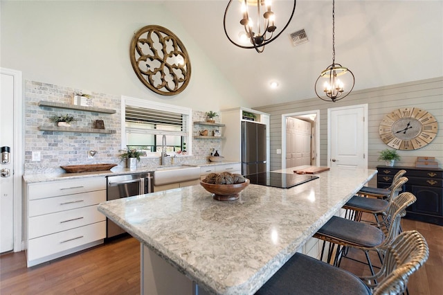 kitchen featuring visible vents, open shelves, a chandelier, a breakfast bar, and stainless steel appliances