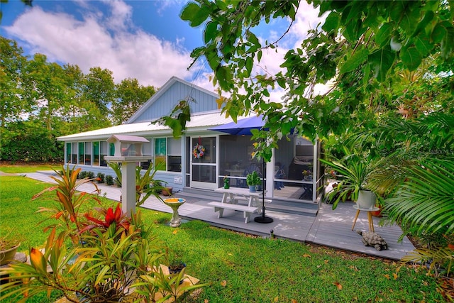 rear view of property with a lawn, a wooden deck, and a sunroom