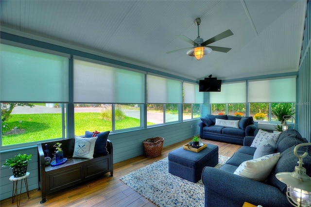 sunroom with wood-type flooring, vaulted ceiling, a wooden deck, and a healthy amount of sunlight