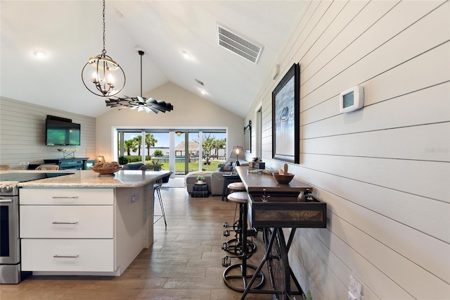 1395 S Lake Reedy Blvd, Frostproof, FL 33843 - kitchen with open floor plan, stainless steel range with electric cooktop, a chandelier, white cabinets, and wooden walls