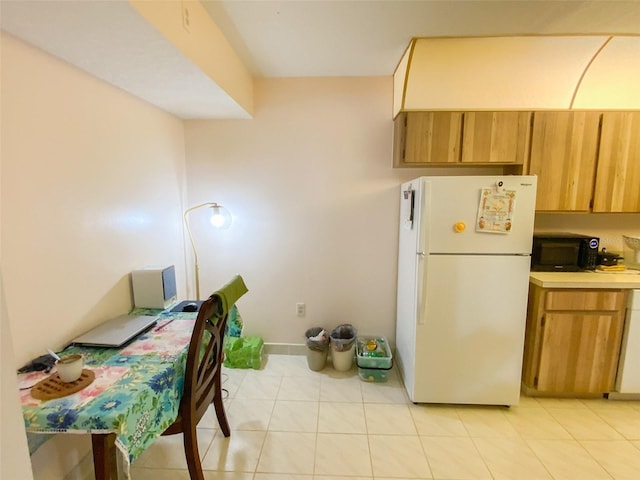 2643 Pine Ridge Way S Unit A1, Palm Harbor, FL 34684 - kitchen with brown cabinets, light tile patterned floors, black microwave, light countertops, and freestanding refrigerator