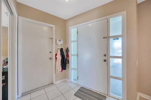 entryway featuring baseboards, light tile patterned floors, and a healthy amount of sunlight