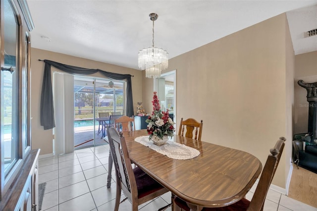 dining room featuring baseboards, a chandelier, light tile patterned floors, and visible vents