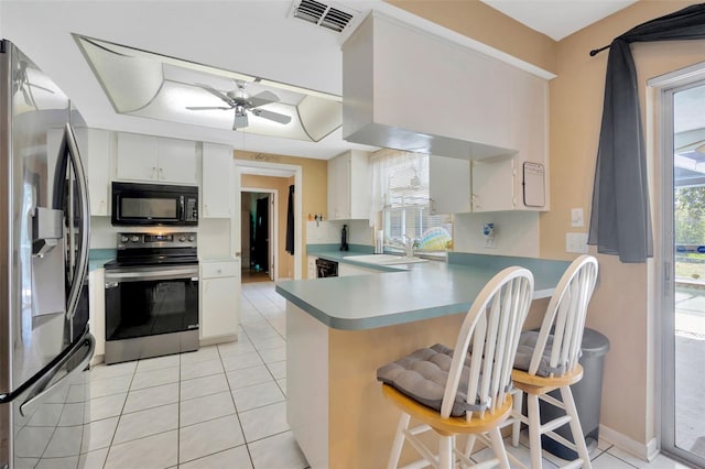 kitchen featuring light tile patterned flooring, appliances with stainless steel finishes, a sink, a peninsula, and visible vents