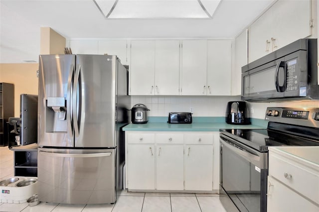 kitchen with light countertops, light tile patterned flooring, white cabinets, and stainless steel appliances