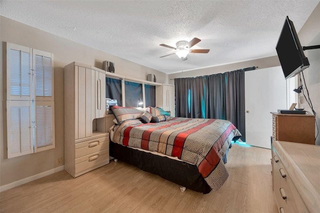 bedroom featuring light wood-style floors, baseboards, ceiling fan, and a textured ceiling