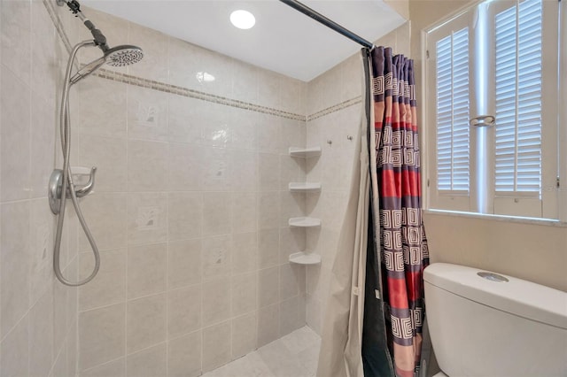 bathroom with a tile shower and toilet