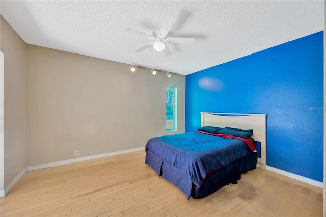 bedroom with hardwood / wood-style flooring, rail lighting, and a textured ceiling