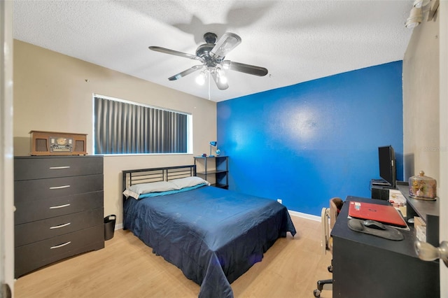 bedroom with a textured ceiling, ceiling fan, and wood finished floors