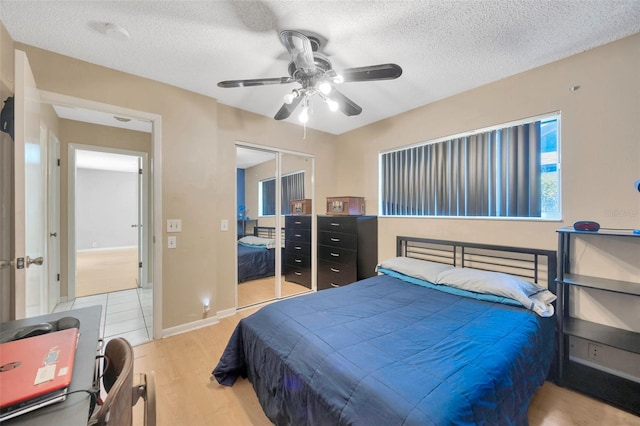 bedroom featuring a closet, ceiling fan, a textured ceiling, and light wood-type flooring