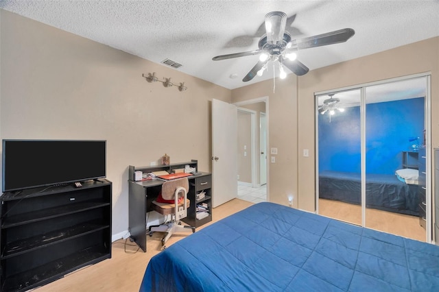 bedroom featuring a ceiling fan, light wood finished floors, a textured ceiling, and visible vents