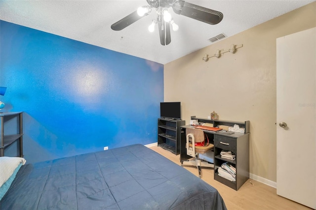 bedroom featuring baseboards, a ceiling fan, wood finished floors, and visible vents