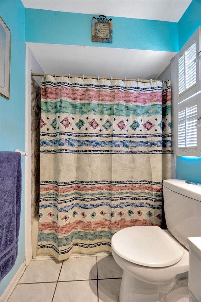 bathroom featuring tile patterned floors, toilet, and curtained shower