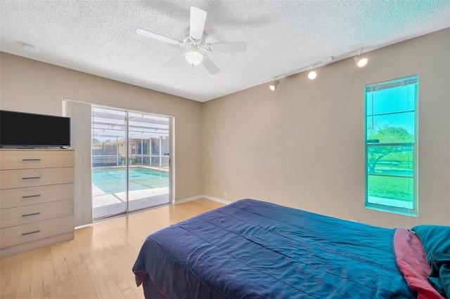 bedroom featuring track lighting, a textured ceiling, access to exterior, a ceiling fan, and wood finished floors